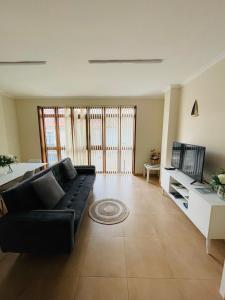 ein Wohnzimmer mit einem schwarzen Sofa und einem TV in der Unterkunft VIVE HOME Vilanova de Arousa in Vilanova de Arousa