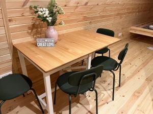 un tavolo in legno con quattro sedie e un vaso con fiori di Camping pod Tiny House aan het water a Belt-Schutsloot