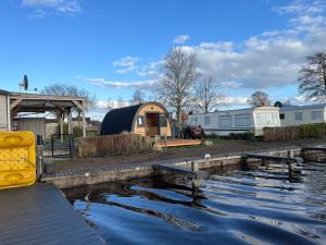 a view of a camp site with a pond and a trailer at Camping pod Tiny House aan het water in Belt-Schutsloot