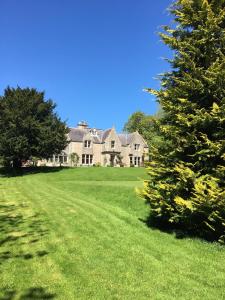 una casa grande en un campo verde con árboles en Whitchester Christian Centre, en Hawick