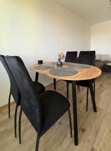 uma mesa de madeira com cadeiras pretas e um sofá em Apartament Kasia em Wałbrzych