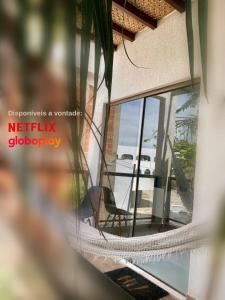 a hammock in front of a window with a view of the ocean at Casa Amora in Arraial do Cabo