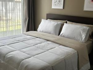 ein Bett mit weißer Bettwäsche und Kissen in einem Schlafzimmer in der Unterkunft Tropical Sunshine known as Amaranto in Alajuela