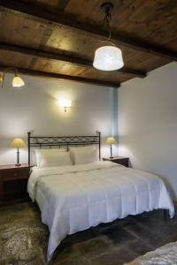 a bedroom with a large white bed with two lamps at Porto Kale Guesthouse in Porto Kagio