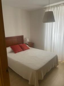 um quarto com uma cama com uma almofada vermelha em Casa dos playas Espasante em Porto de Espasante