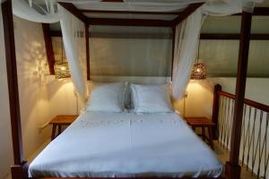 a bed with white sheets and pillows in a room at Sanjana & Julien's in Tamarin