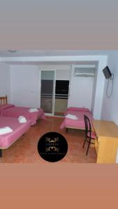 a room with pink beds and a table and chairs at Hotel COSTAS in Fortuna
