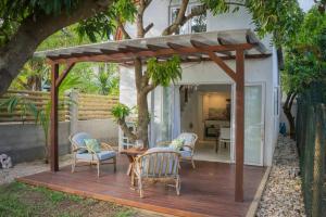 a wooden deck with chairs and a table in a backyard at Sanjana & Julien's in Tamarin