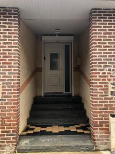 um corredor com uma porta branca e escadas com uma parede de tijolos em Loveroom la crèche romantique em Bogny Sur Meuse