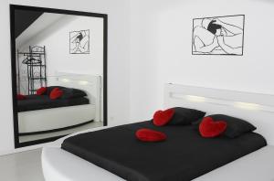 - une chambre avec 2 lits dotés d'oreillers rouges et d'un miroir dans l'établissement Loveroom la crèche romantique, à Bogny Sur Meuse