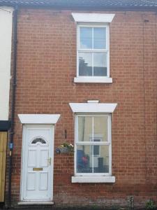 un edificio de ladrillo con dos ventanas y una puerta blanca en The Cosy Home in Burton. Sleeps 5. Fast Wi-fi, en Burton upon Trent