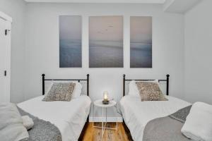 two beds in a room with three pictures on the wall at Stylish Suite-NearWEM-4 Bed-Central in Edmonton