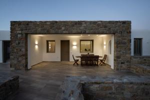 a patio with a table and chairs and a brick wall at Maistros Apartments Mykonos in Ftelia