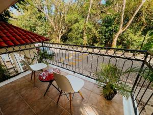 un balcón con 2 sillas, mesas y árboles en Che Suites Playa Adults Only en Playa del Carmen