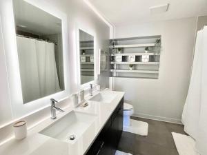 a white bathroom with two sinks and a toilet at The Perfect Scenario in Buckhead in Atlanta