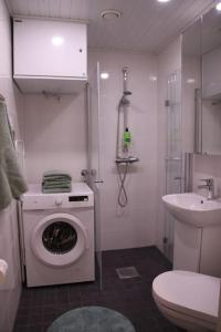 een badkamer met een wasmachine en een wastafel bij Kodikas hyvin varusteltu yksiö, autopaikalla in Vantaa