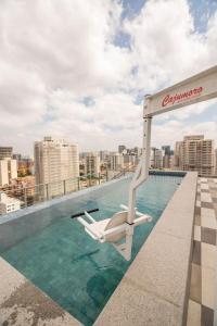 a white chair sitting on the edge of a swimming pool at Metro Brooklin - Be Urban in Sao Paulo