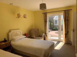 1 dormitorio con cama, silla y puerta corredera de cristal en Whitchester Christian Centre, en Hawick