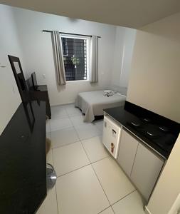 a small white room with a bed and a window at Apartamentos centrais junto ao calçadão in Ponta Grossa