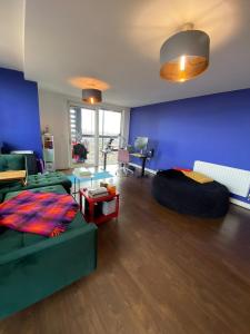 a living room with a green couch and a blue wall at Quirky 1BD Flat wGym & City Views Dalston! in London