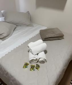 Una cama blanca con toallas blancas y zapatos. en Apartamento 2 quartos c/ garagem, en Ponta Grossa