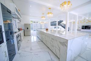 a kitchen with white marble counter tops and chandeliers at El AMO LAKEVIEW VILLA in Entebbe