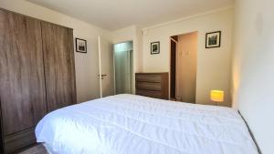 1 dormitorio con cama blanca y puerta de madera en Résidence La Petite Ourse - 3 Pièces pour 6 Personnes 62, en Flaine