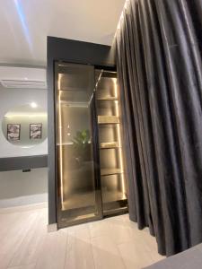 a glass refrigerator in a room with a curtain at San Vito Luxury apartment in Sowayma