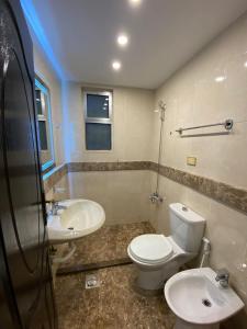 a bathroom with a toilet and two sinks at San Vito Luxury apartment in Sowayma