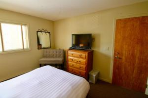Dormitorio con cama y tocador con TV en Timberline Condos - Aspen Building en Fernie