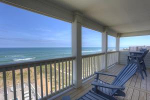 a porch with two blue rocking chairs and the ocean at TSC404 Seaclusion Oceanfront Elevator in Kill Devil Hills