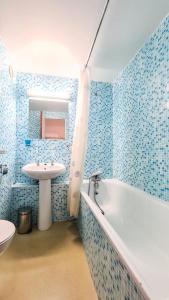 a blue tiled bathroom with a tub and a sink at Résidence Andromede - Studio pour 4 Personnes 05 in Flaine