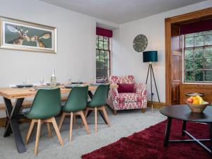 ein Esszimmer mit einem Tisch und grünen Stühlen in der Unterkunft Watermouth Castle, Rhododendron Apartment in Ilfracombe