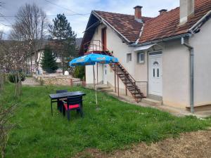 a table with an umbrella next to a house at Apartman Sadba in Goražde