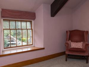 einen Stuhl in einem Zimmer mit Fenster in der Unterkunft Watermouth Castle, Rhododendron Apartment in Ilfracombe