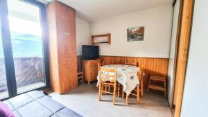 a room with a table with chairs and a television at Résidence Doris - Studio pour 4 Personnes 04 in Flaine