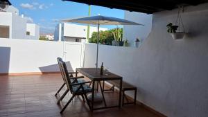 a table and chairs with an umbrella on a balcony at Casa Mar Azul. in Tinajo