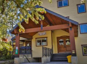 a yellow house with a wooden entrance to it at Timberline Condos - Aspen Building in Fernie