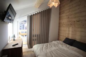 1 dormitorio con 1 cama, TV y ventana en Les Chalets Du Grand Galibier - 4 Pièces pour 8 Personnes 94 en Valloire