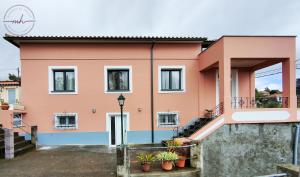 uma casa rosa com escadas e um relógio em Magnólia House em Santa Cruz - Madeira