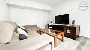 uma sala de estar com um sofá e uma televisão em Magnólia House em Santa Cruz - Madeira