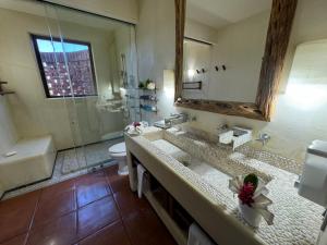 a bathroom with a sink and a toilet and a mirror at Residences at Las Palmas in Zihuatanejo