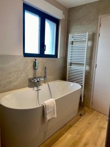 a white bath tub in a bathroom with a window at La Cremaillere Hôtel-Restaurant in Courseulles-sur-Mer