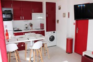 uma cozinha com armários vermelhos e electrodomésticos brancos em Résidence La Croix Du Sud - Studio pour 4 Personnes 44 em Valloire