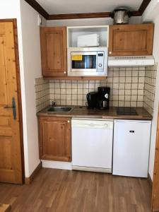 uma cozinha com electrodomésticos brancos e armários de madeira em Résidence Gentiane Hameau De La Vallee D'or - 2 Pièces pour 4 Personnes 84 em Valloire