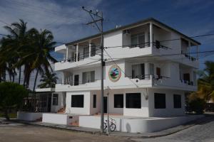 ein weißes Gebäude mit einer Palme davor in der Unterkunft Hostal Las Fragatas in Puerto Villamil
