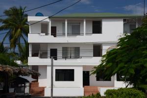 a white building with a balcony and a palm tree at Hostal Las Fragatas in Puerto Villamil