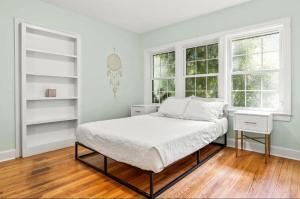 a white bedroom with a bed and two windows at The Peacock House - Close to Restaurants and Shops in Greensboro