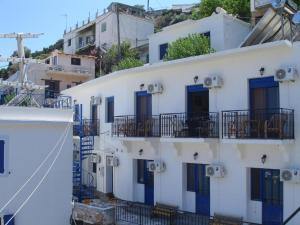 um grupo de edifícios brancos com portas e janelas azuis em Lydia Mare em Agios Kirykos