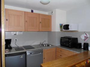 a kitchen with wooden cabinets and a sink and a microwave at Résidence Belvedere - 2 Pièces pour 6 Personnes MAE-4664 in Modane +3 photos